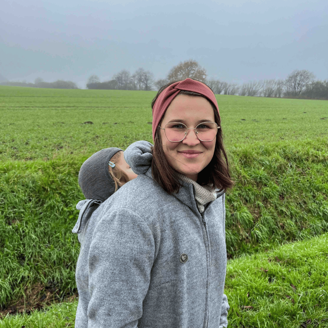 Mama mit Baby in der Trage und Tragejacke